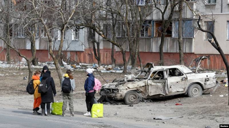 Los refugiados se reúnen en una calle cuando salen de la ciudad durante el conflicto entre Ucrania y Rusia en el asediado puerto sur de Mariupol, Ucrania, el 20 de marzo de 2022. REUTERS/Alexander Ermochenko